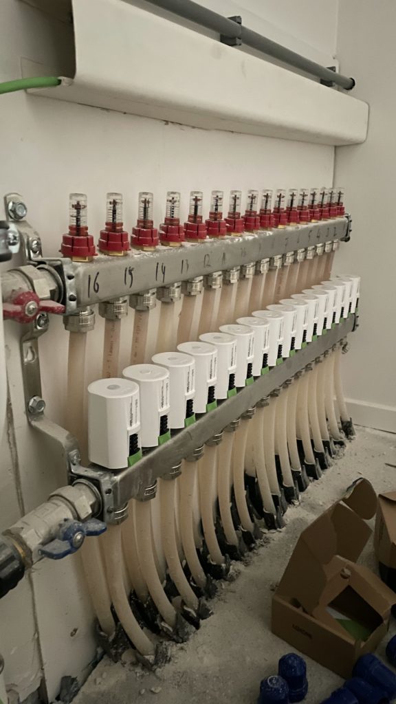 Vloerverwarmingsverdeler met actuatoren tijdens de werkzaamheden.